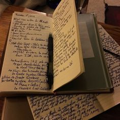 two notebooks with writing on them are sitting on a table next to a pen