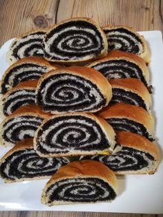 a white plate topped with rolls covered in black and white icing on top of a wooden table