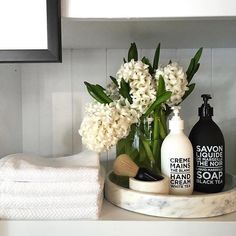 a bathroom counter with soap, lotion and flowers in a glass vase on it