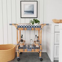 a bar cart with bottles and glasses on it in a kitchen next to a potted plant