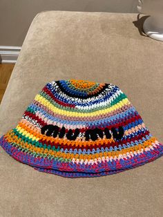 a multicolored crocheted hat sitting on top of a couch next to a wall