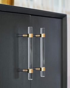 a black cabinet with two brass handles and some glass door knobs on the front