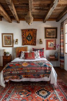 a large bed sitting under a wooden ceiling in a bedroom next to two paintings on the wall