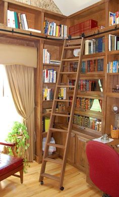 a living room filled with lots of wooden bookshelves next to a red chair