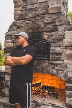 a man standing in front of an outdoor fireplace