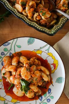 a plate with shrimp and sauce on it next to a bowl full of other food