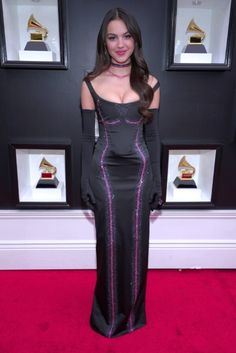 a woman in a black and pink dress on the red carpet at an awards event