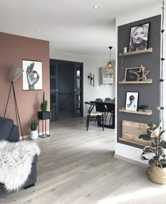 a living room filled with furniture next to a dining table and two pictures on the wall