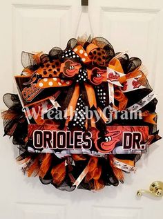 an orange and black wreath with the word orioles on it is hanging on a door