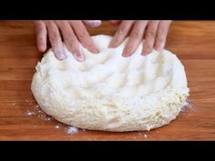 someone kneading dough on top of a wooden table