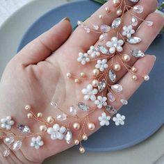 a woman's hand holding some pearls and flowers on her palm with other items in the background