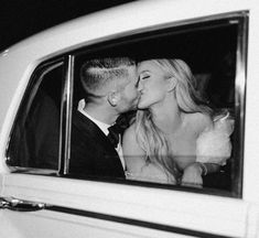 a man and woman kissing in the back of a car