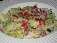 a salad with lettuce, tomatoes and other toppings on a white plate