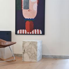 a chair sitting in front of a painting on the wall next to a marble block