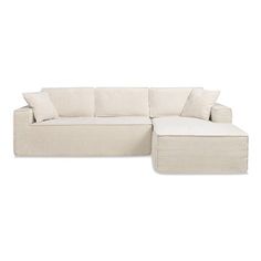 a white couch with pillows on top of it and a footstool next to it