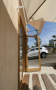 a car is parked in front of a building with an umbrella over the entrance door