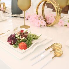 a white plate topped with fruit and veggies on top of a table next to gold utensils