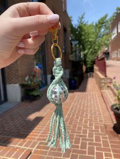 a person is holding up a key chain with a ball hanging from it's end