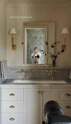 a person taking a photo in a bathroom mirror with a camera on the counter top