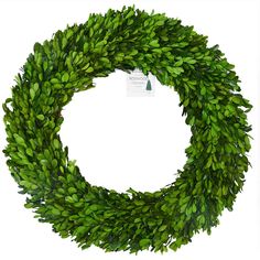 a green wreath is hanging on a white wall and it has a tag that says,