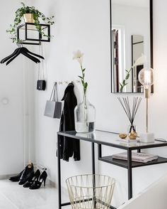 a black and white entryway with shoe rack, mirror and vase on the wall