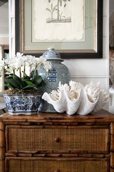 a blue and white vase sitting on top of a table next to a potted plant