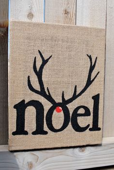 a canvas with the word noel painted on it and a deer's antlers