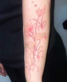 a woman with a tattoo on her arm has pink flowers and leaves painted on it