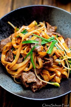 beef and noodles are served in a black bowl