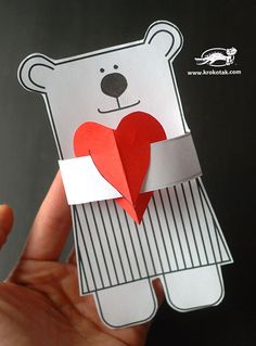 someone is holding up a paper bear with a heart