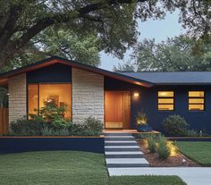 a blue house with steps leading up to the front door and trees in the yard