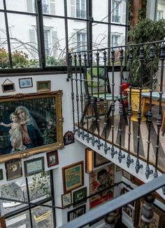 a staircase with pictures and paintings on the wall next to it in a building that has many windows