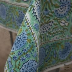 an image of a blue and green floral print table cloth on a wooden chair or bench