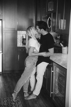 black and white photograph of two people kissing in the kitchen