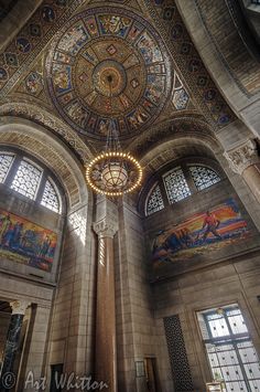 an ornate ceiling with paintings and chandelier in a building that has many windows