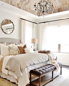 a bedroom with a large bed and a chandelier hanging from it's ceiling