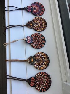 four handmade wooden ornaments are lined up on a white door way with string attached to them