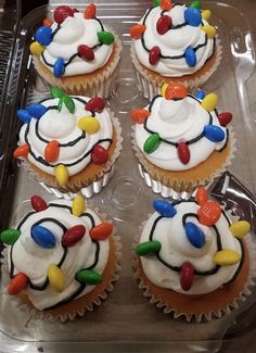 cupcakes with white frosting and colorful lights on them in a plastic container