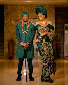 two people standing next to each other wearing green and gold outfits with beads on them