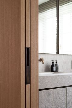 a bathroom with a sink, mirror and wooden cabinetry in the middle of it