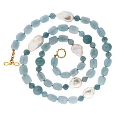 An array of blue displays the varied shades of aquamarine. The pattern begins with five irregularly shaped beads of pale blue. This follows with a baroque white pearl, emitting its satin radiance, in between two roundels of blue-gray. Next, three more pale blue beads lead to an orb of deep blue in between two roundels of the same shade. The pattern finishes with five pale blue beads. The total weight of the gems is 56 carats of aquamarine and 5 carats of freshwater pearls. An 18k yellow gold kno Large Bead Necklace, Fresh Water Pearl Necklace, Necklaces Beaded, Water Pearl Necklace, 1st Dibs, Pearl Beaded Necklace, Gold Baroque, Vintage Beads Necklace, Aquamarine Necklace