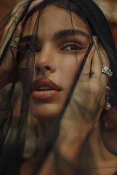 a woman with her hands on her face and veil over her head, looking off to the side