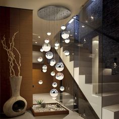 a staircase with glass balls hanging from it's sides and a vase on the floor