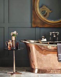 a bathroom with a copper bathtub and side table