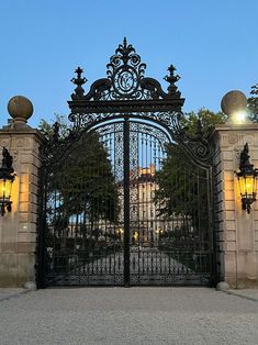 an iron gate with two lamps on each side