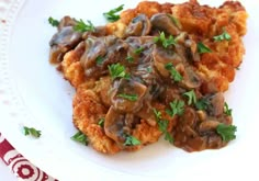 a white plate topped with meat covered in mushroom gravy