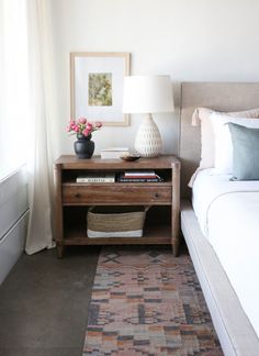 a bedroom with a bed, nightstand and lamp on the side table next to it