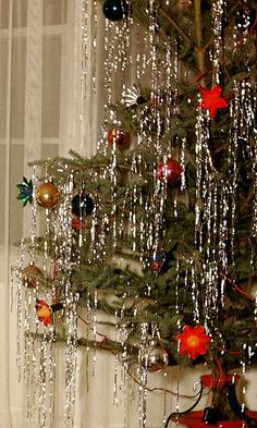 a small christmas tree with ornaments hanging from it's branches in front of a window