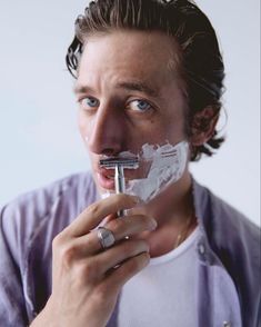 a man is shaving his face with an electric razor and toothpaste on his mouth