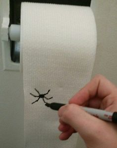 a person is drawing on a toilet paper roll with a black marker and it looks like a bug